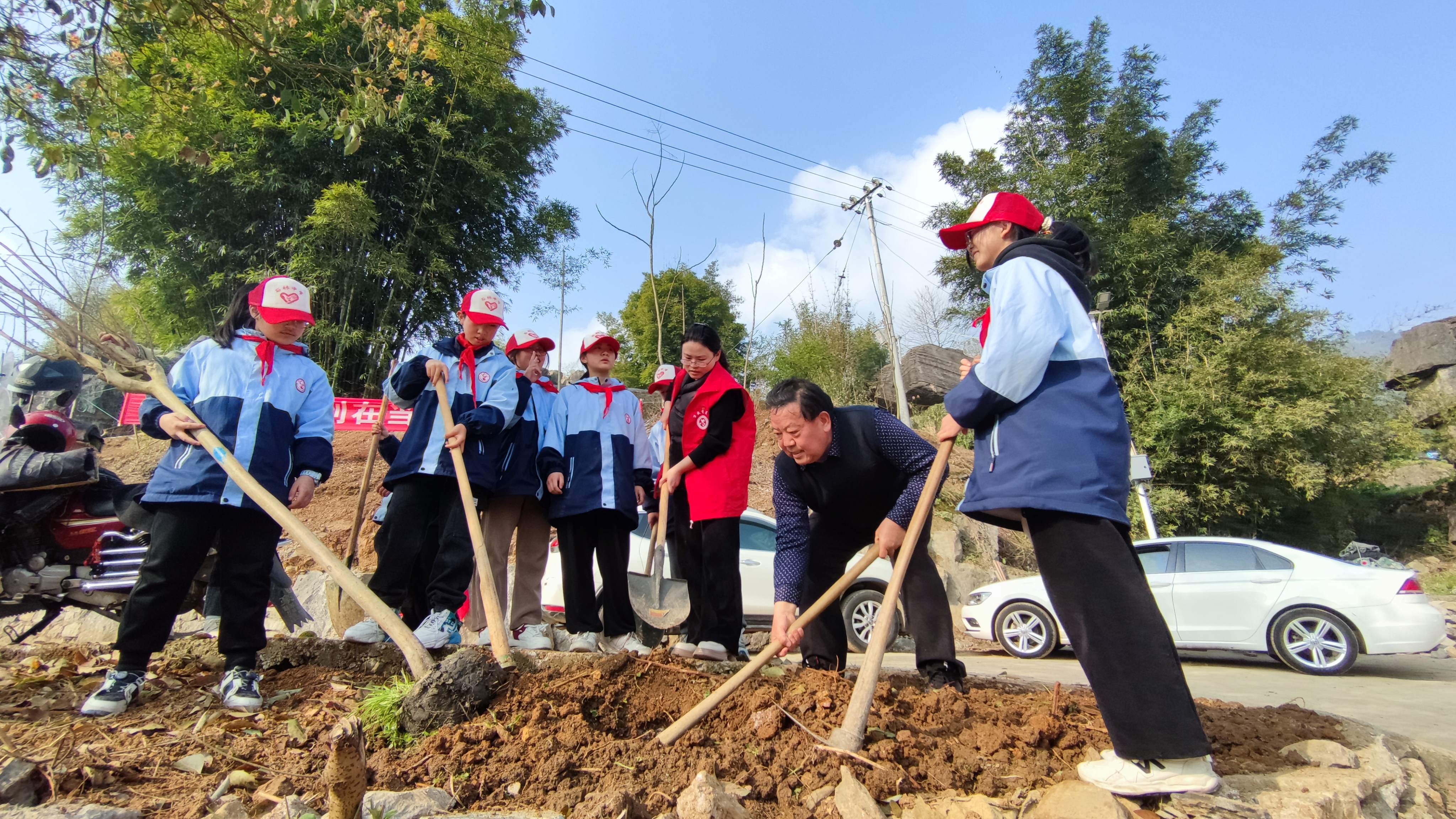 3月11日，重庆市万盛经开区石林镇关工委、石林中学关工委联合开展“共建绿色生态，共享美丽家园”植树活动。镇关工委常务副主任曾庆财（右二）手把手指导孩子们栽种树木。1.jpg