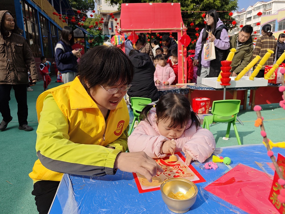 1770108564756701.jpg 【非遗庙会迎新春 传统文化润童心】“五老”志愿者协助小朋友拓印吉祥图案1.jpg